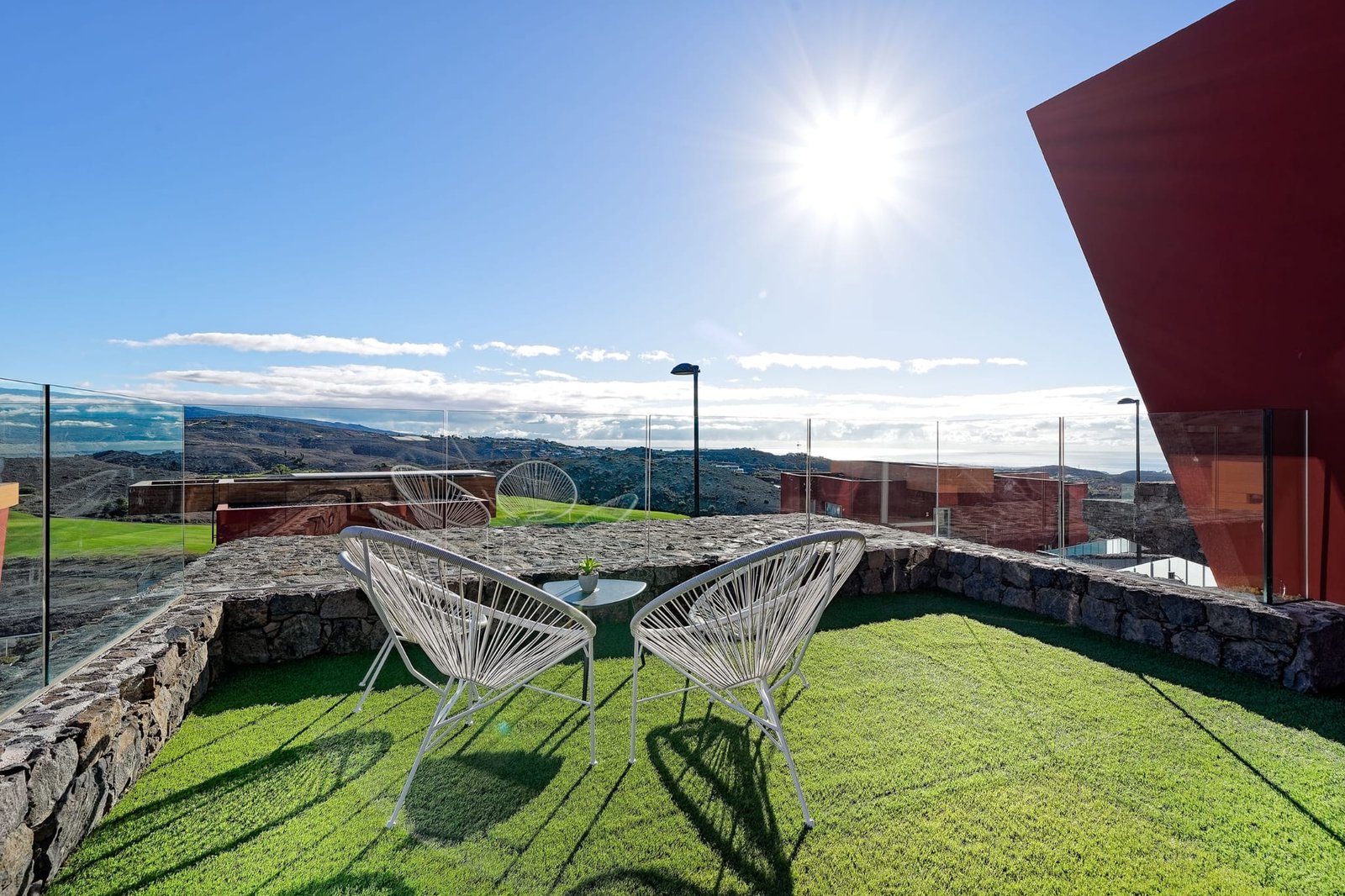 Terrace with mountain and sea views in the background, with two very handcrafted chairs to contemplate the views, and with a grass floor - Villa Estación 1 - Salobre Resort
